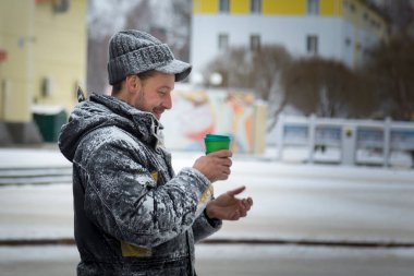 Elinde bir bardak sıcak kahveyle siyah şapkalı bir işçinin portresi.