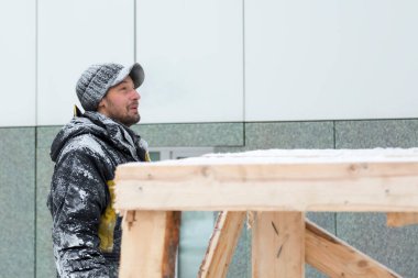 Elinde bir bardak sıcak kahveyle siyah şapkalı bir işçinin portresi.