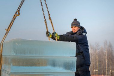 Mavi ceketli Slinger derleyicisi buz panellerini boşaltıyor.