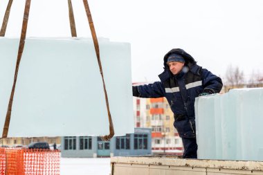 Mavi ceketli Slinger derleyicisi buz panellerini boşaltıyor.
