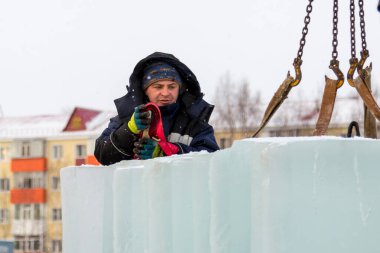 Mavi ceketli Slinger derleyicisi buz panellerini boşaltıyor.
