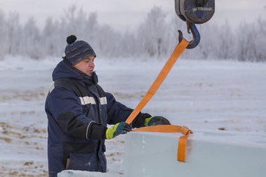 Slinger yükleyici kancaya bir bant halatı takar.
