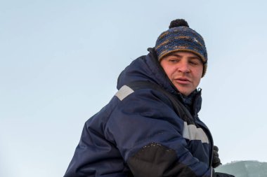 İş yerinde mavi kışlık ceketli bir adamın portresi.