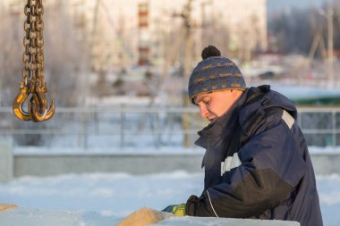 Mavi ceketli Slinger derleyicisi buz panellerini kamyon vinçiyle boşaltıyor.