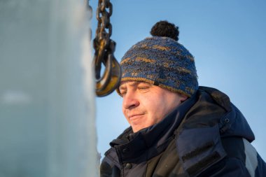 Mavi ceketli bir işçi fırlatıcısının portresi zincir örümceği kullanarak buz kalıplarını boşaltıyor.