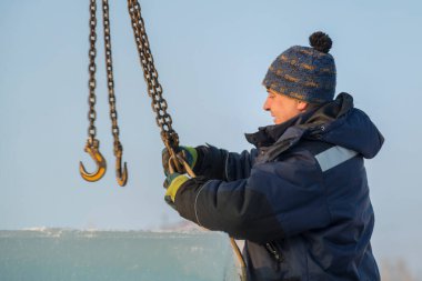 Mavi ceketli bir işçi fırlatıcısının portresi zincir örümceği kullanarak buz kalıplarını boşaltıyor.