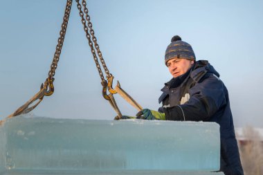 Mavi ceketli bir işçi fırlatıcısının portresi zincir örümceği kullanarak buz kalıplarını boşaltıyor.