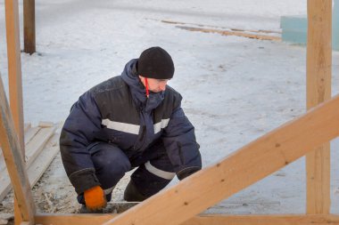 İşçi derleyici bir mezura ile tahtayı işaretler