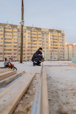 İşçi derleyici bir mezura ile tahtayı işaretler