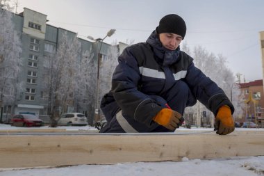 İşçi derleyici bir mezura ile tahtayı işaretler