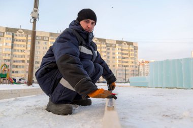 İşçi derleyici bir mezura ile tahtayı işaretler