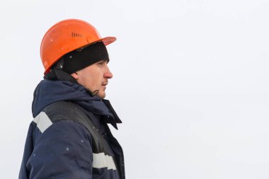 Yorganlı bir tesisatçının yakın plan portresi ve kafasında turuncu bir miğfer.