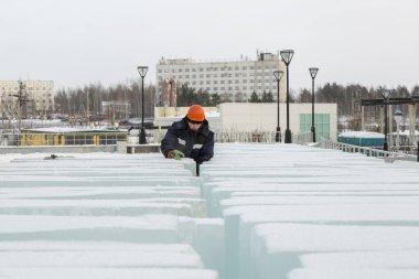Turuncu kasklı bir işçi buz bloklarını geçmeye çalışıyor.