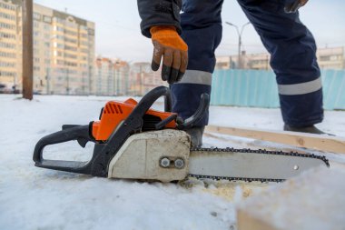 Mavi ceketli bir montajcı ahşap kirişlerden yapılmış bir kaydırağın çerçevesini monte eder.