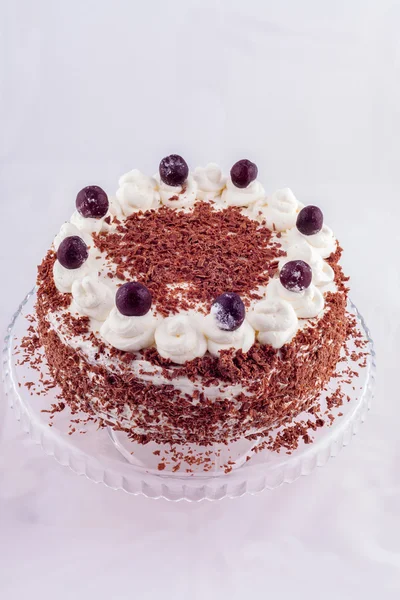 Black forest cake decorated with whipped cream and cherries.