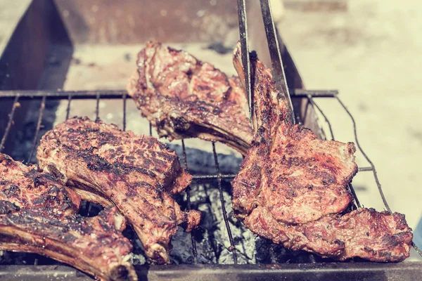 Carne prăjită pe grătar cu mâna masculină . — Fotografie, imagine de stoc