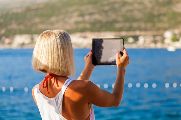 Κορίτσι κάνει σέλφι φωτογραφίες με ένα tablet στη θάλασσα — Φωτογραφία Αρχείου