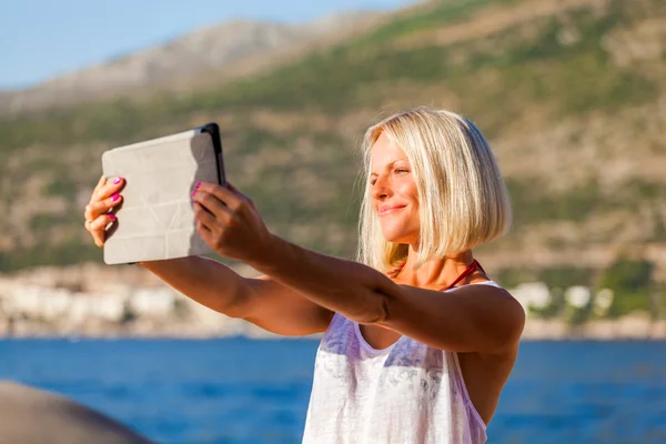 Κορίτσι κάνει σέλφι φωτογραφίες με ένα tablet στη θάλασσα — Φωτογραφία Αρχείου