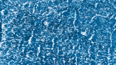 Mavi buz yüzeyinde çizikler ve kar var.