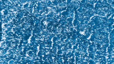 Mavi buz yüzeyinde çizikler ve kar var.