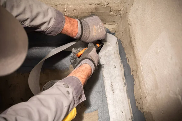 Aplicando uma fita de impermeabilização para a articulação entre a parede e o chão. Obras de construção interna — Fotografia de Stock