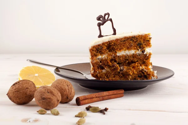 Piece of carrot cake with walnuts and white cream.