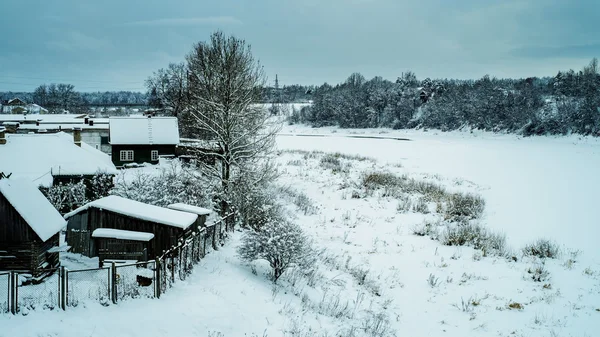 Besneeuwde dorp aan de oever van de rivier — Stockfoto