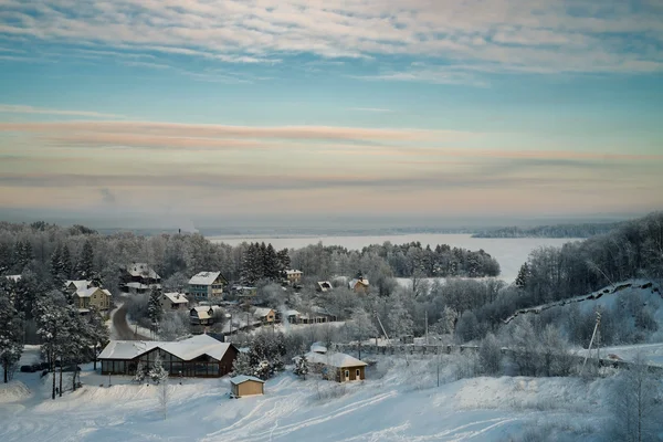 Besneeuwde bos en huisjes en iced lake bij zonsondergang — Stockfoto