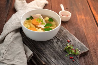 Makarnalı tavuk çorbası, havuç, maydanoz ve ahşap zemin üzerinde et parçaları. Ev yapımı köy çorbası.