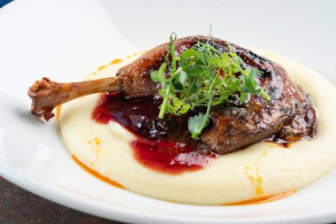 Yaban mersini soslu patates püresiyle pişirilmiş ördek bacağı.