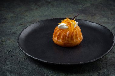 Krem şantili ve siyah tabakta portakallı bisküvi tatlısı.