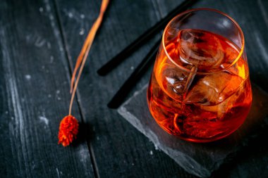 Koyu ahşap arka planda turuncu ve buzlu bir Aperol şırıngası.