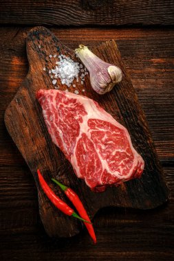 Tahta üzerinde çiğ demir biftek, kırmızı biberli, üst manzara.