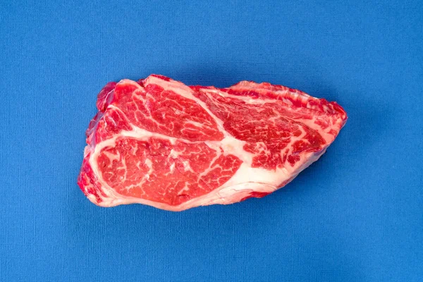 蓝色背景上方的新鲜生牛肉牛排 — 图库照片