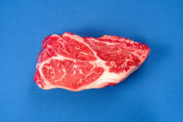 Fresh raw beef steak on a blue background top view