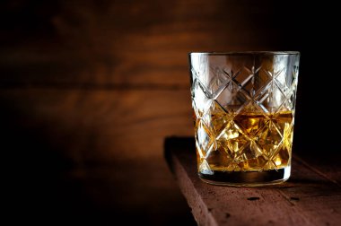 Eski ahşap bir masada buzlu yarım bardak viski, köy usulü.