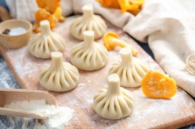 Pişmemiş Gürcistan köftesi ya da mantarlı khinkali ve ahşap kesim tahtasında domuz eti.