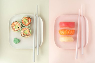 Çeşitli suşi setleri ve yemek çubuklarıyla bir tabakta yuvarlanmalar. Somonlu suşi, ton balığı ve istiridye, modern görünüm.