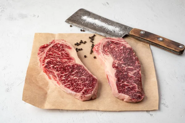 İki çiğ mermer biftek New York bifteği ve bir et satırı.