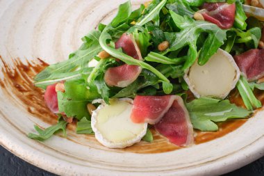 Taze salata roka, Parma jambonu ve tabakta yumuşak peynir, İtalyan mutfağı, yakın çekim.