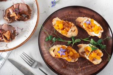 Izgara kabaklı, peynirli ve incili arpalı kızarmış ekmek tabağında, en üstte.