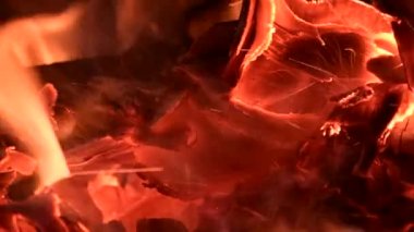 Yanan bir kamp ateşine yakın çekim, gece ateşi, kütükler, kontrplak ve kumaş yanıyor, rüzgarın esintisi kıvılcımları patlatıyor, ağır çekim HD video