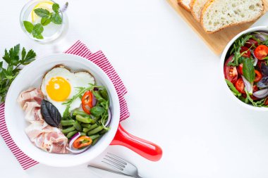 Avrupa kahvaltısı: kalp şeklinde yumurta, pastırma, beyaz masada yeşil fasulye. Seçici odaklanma. Yukarıdan bak. Boşluğu kopyala.