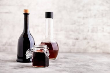 Mermer bir masanın üzerinde beyaz tuğla bir duvarın arka planında farklı sirke bulunan orijinal cam şişeler. Uzayı kopyala Yatay.