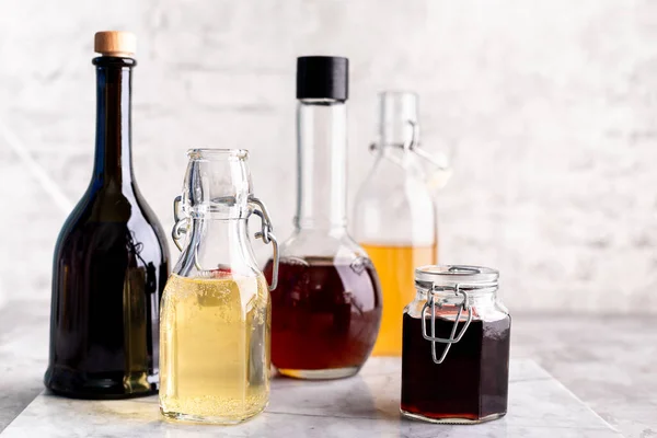 Originele Glazen Flessen Met Verschillende Azijn Een Marmeren Tafel Tegen — Stockfoto