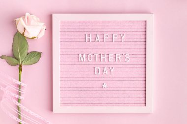 Pembe Keçeli Harf Tahtasında Mutlu Anneler Günleri. Bir buket gül ve gri arka planda hediye olan bir kutuyla şenlik kompozisyonu. Üst manzara, düz yatış. Boşluğu kopyala.