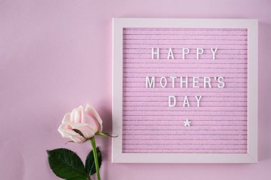 Pembe Keçeli Harf Tahtasında Mutlu Anneler Günü. Bir buket gül ve pembe arkaplanlı bir kutuyla kutlama kompozisyonu. Üst manzara, düz yatış. Boşluğu kopyala.