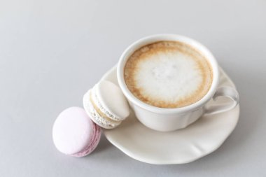 Gri ve pembe arka planda kek için bir fincan kahve, makarna. Boşluğu kopyala.