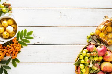 Sonbahar arkaplanı beyaz ahşap bir masada şekerli şuruplu cennet elmaları. Sonbahar hasadını hasat ediyorum. Cennet elma reçeli. Üst Manzara. Boşluğu kopyala.