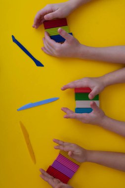 Bir grup şirin anaokulu öğrencisi renkli killere dikey dokunuyor.